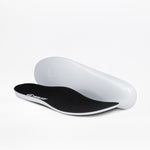 A pair of insoles for the Men's Taupe BILLY Inclusion Trail Boot by BILLY Footwear is pictured on a white background, with one insole flat and the other upright to show the black top and white bottom.
